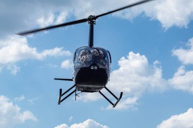 Bulutlu mavi gökyüzü arka planında gezinen modern siyah helikopter