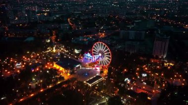 Gece vakti aydınlatmalı dönme dolap ile lunaparkın hava sineması görüntüleri.