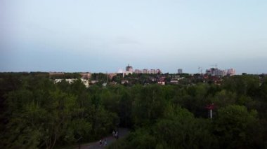 Akşam yerleşim bölgesinde yeşil parkın üzerinde uçan bir hava aracı var.