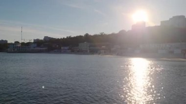 Akşam güneşi Odesa şehrinde kumlu bir plajda ılık bir şekilde parıldıyor. Yumuşak dalgalar ve altın ışıkla.