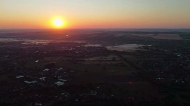 Kırsal alanların ve evlerin üzerindeki temiz gökyüzünde gün doğumu güneşi.