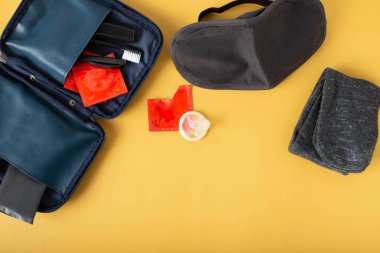 Top view,Men Bag with essentials for modern men person on white table .leather bag, smartphone,power bank, notepad, book,keys, medicine pills with Condom Concept for Save sex