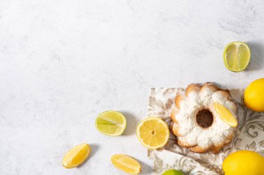 Limon muffin round hole with white icing and pomegranate on a white table.