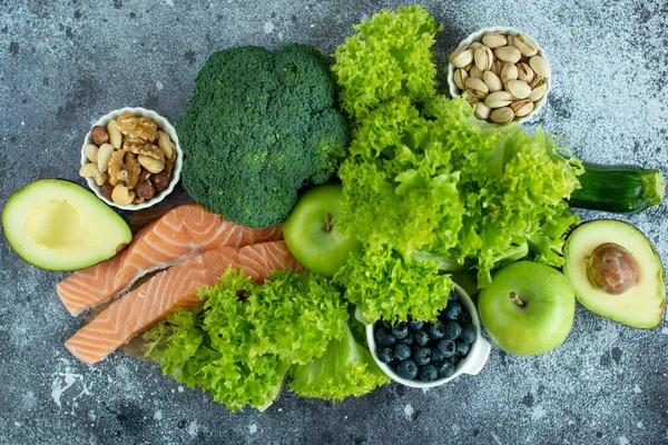 Healthy food clean food selection: fruits, vegetables, superfoods, salmon fish, leafy vegetable on gray concrete background