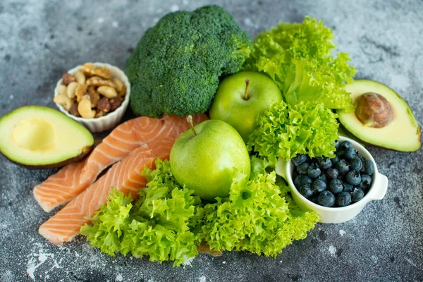 Healthy food clean food selection: fruits, vegetables, superfoods, salmon fish, leafy vegetable on gray concrete background