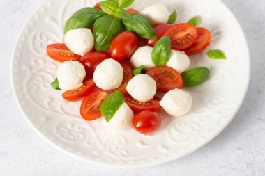 Beyaz arka planda caprese salatası. mozzarella ve vişneli domates. Domatesli salata, mozzarella ve fesleğen.