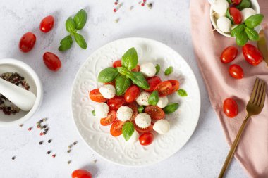 Beyaz arka planda caprese salatası. mozzarella ve vişneli domates. Domatesli salata, mozzarella ve fesleğen.