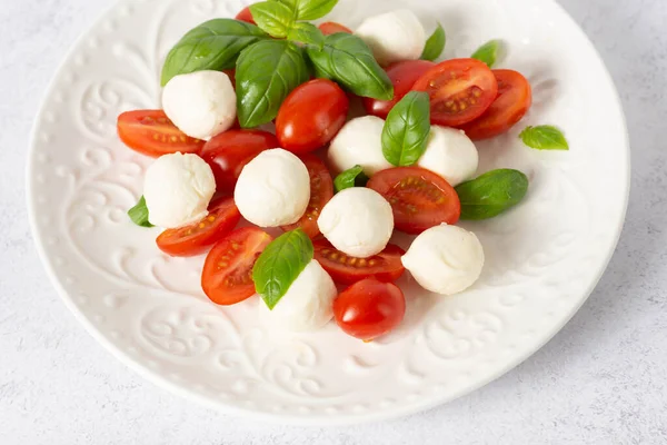 Beyaz arka planda caprese salatası. mozzarella ve vişneli domates. Domatesli salata, mozzarella ve fesleğen.
