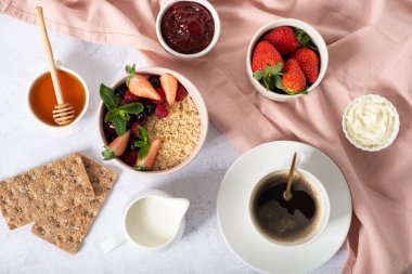 Sağlıklı kahvaltı malzemeleri. Açık cam kavanozda ev yapımı granola, süt ya da yoğurt şişesi, beyaz ahşap arka planda yaban mersini ve nane, üst manzara, kopyalama alanı