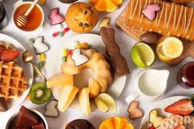 Kuş yuvasında çikolata yumurtaları ve paskalya bademleri, çikolatalı tavşanlar ve beyazda tatlılar. Paskalya tablosu