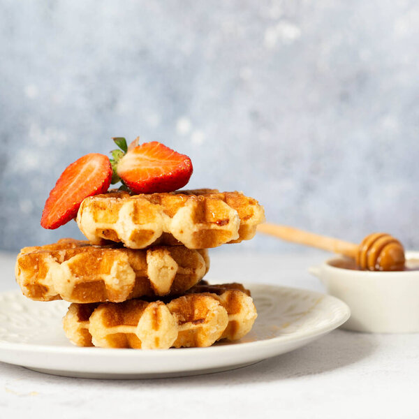 Belgian waffles with strawberries and powdered sugar.