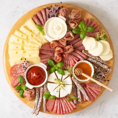 Kahverengi arka planda yuvarlak bir kesme tahtasında sosis ve peynir dilimleme. Kopyalama alanı olan yan görünüm.