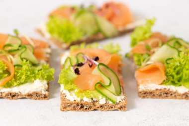 Beyaz taş bir masada tuzlanmış somon ve salatalıklı çavdar ekmekli sandviç. Sağlıklı yemek..