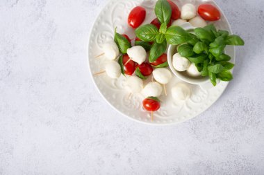 Mozzarella peyniri topları, domatesler, fesleğen yaprakları ve beyaz arka planda uçuşan caprese salatası için biberler. Pankart tasarımı
