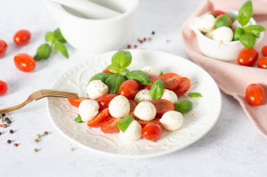 Dilimlenmiş domatesli İtalyan caprese salatası, mozzarella, fesleğen, hafif arka planda zeytinyağı. Caprese salatası
