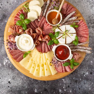 Lezzetli. Peynir, prosciutto, beton arka planda ahşap bir tahta üzerinde salam..