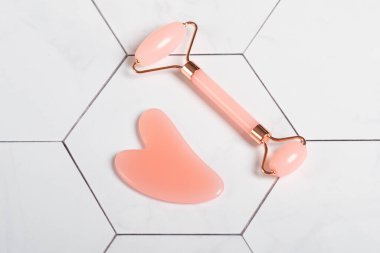 Yüz masajı seti. Yeşim taşı ve ametist gua sha 'dan yapılmış alet ve silindir. Yüz silindiri, doğal taştan yapılmış masaj aleti..