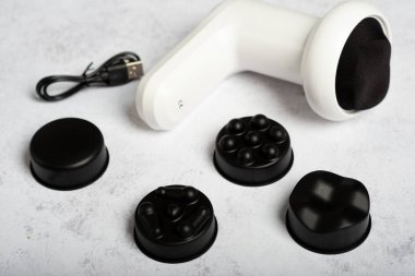 Beyaz bir arka planda perküsyon masaj tabancası. Kaslardaki gerilimi azaltmak için perküsyon titreşim masaj aleti. Vücut masajcısı..