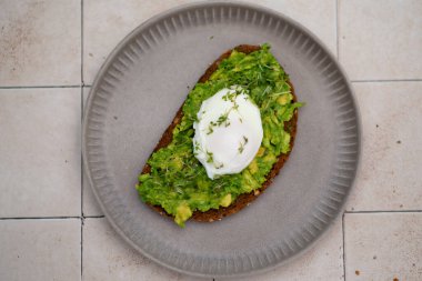 Avokado tostu, tabakta yumurta, açık fayans masası, üst manzara..