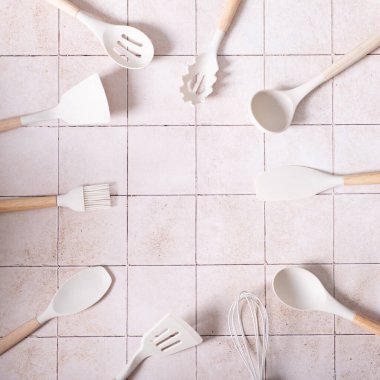 Mutfak takımının arka planında spatula var. Beyaz zemin üzerinde farklı mutfak çatal bıçak takımları olan kompozisyon