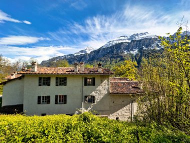 Açık avlusu olan geleneksel Avrupa çiftlik evi, çeşitli seviyelerde balkonlar, açık kirişler ve parlak mavi gökyüzüne karşı dizilmiş eski ahşap tarım arabaları.