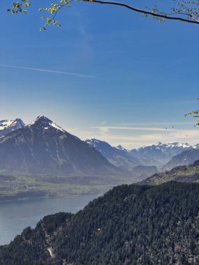 Geleneksel bir binası ve gün batımında karla kaplı dağları olan bir tepenin yanındaki göl kenti manzarası.
