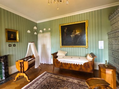 Yüksek tavanlı görkemli bir yemek odası, uzun ve zarif bir masa. Duvarlar portre ve geyik boynuzlarıyla süslenip sofistike ve görkemli bir atmosfer yaratıyor.