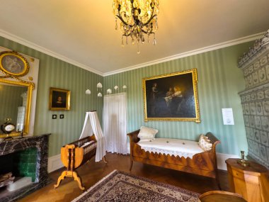 Yüksek tavanlı görkemli bir yemek odası, uzun ve zarif bir masa. Duvarlar portre ve geyik boynuzlarıyla süslenip sofistike ve görkemli bir atmosfer yaratıyor.