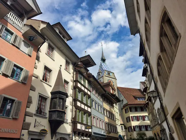 stock image Cozy street in a European town with historic buildings and colorful architecture. The scene features a decorative fountain in the foreground and charming facades of old houses.