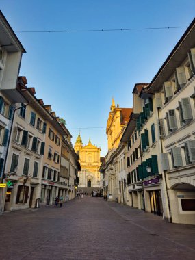 28.07.24 Switzerland. Günbatımında, temiz bir gökyüzünün altında tarihi bir saat kulesi ve çevresindeki renkli binalar görülüyor.