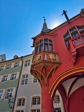 13.07.24.Germany. Gothic-style architecture with intricate details and a prominent spire under a clear blue sky. The sun adds a bright highlight to the scene, enhancing the vibrant colors of the buildings clipart