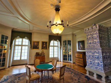 13.07.24 Switzerland. Yüksek tavanlı görkemli bir yemek odası, uzun ve zarif bir masa. Duvarlar portre ve geyik boynuzlarıyla süslenip sofistike ve görkemli bir atmosfer yaratıyor.