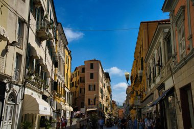 Canlı cepheli renkli binalar, dramatik bir gökyüzü altında manzaralı bir manzara yaratan bir yamaç çiziyor.