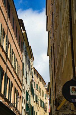 Canlı cepheli renkli binalar, dramatik bir gökyüzü altında manzaralı bir manzara yaratan bir yamaç çiziyor.