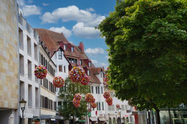 Çiçekleri, büyüleyici binaları ve ağaçları olan eski bir kasaba caddesi.