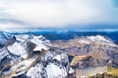 Yoğun sonbahar yaprakları ve canlı kaya dokularıyla kaplı dağ yamaçları.