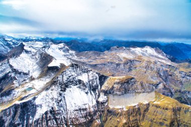 Yoğun sonbahar yaprakları ve canlı kaya dokularıyla kaplı dağ yamaçları.