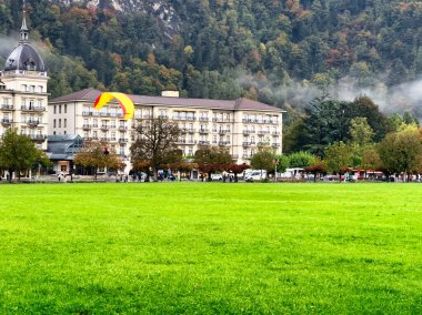 Arka planda dramatik bulutlar, dağlar ve yemyeşil yemyeşil bir çayır.