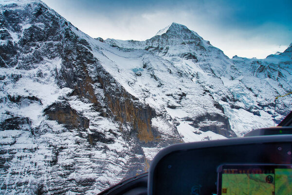 Majestic snow-covered mountains with rugged peaks and dramatic cloudy sky