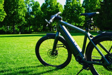 30.05.24.Berns.Wizerland. Yeşil ağaçlar ve mavi gökyüzünün yer aldığı bulanık doğal bir arka planı olan elektrikli bisiklet far ve gidonların yakın çekimi.