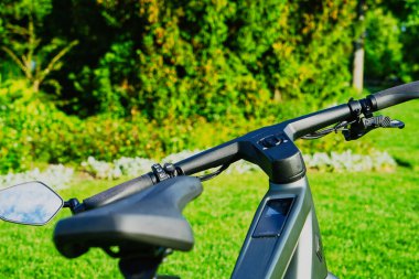 30.05.24.Berns.Wizerland. Yeşil ağaçlar ve mavi gökyüzünün yer aldığı bulanık doğal bir arka planı olan elektrikli bisiklet far ve gidonların yakın çekimi.