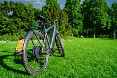 30.05.24.Berns.Wizerland. Yeşil ağaçlar ve mavi gökyüzünün yer aldığı bulanık doğal bir arka planı olan elektrikli bisiklet far ve gidonların yakın çekimi.