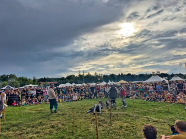 01.06.06.24.Kirchberg.Swizerland. Bir ortaçağ canlandırma etkinliği. Çimenli bir alanda çarpışan zırhlı şövalyeler dramatik bulutlu bir gökyüzü altında izleyicilerle çevrili.