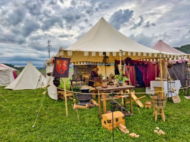 01.06.06.24.Kirchberg.Swizerland. Bir ortaçağ canlandırma etkinliği. Çimenli bir alanda çarpışan zırhlı şövalyeler dramatik bulutlu bir gökyüzü altında izleyicilerle çevrili.