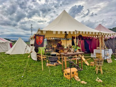 01.06.06.24.Kirchberg.Swizerland. Bir ortaçağ canlandırma etkinliği. Çimenli bir alanda çarpışan zırhlı şövalyeler dramatik bulutlu bir gökyüzü altında izleyicilerle çevrili.
