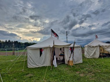 01.06.06.24.Kirchberg.Swizerland. Bir ortaçağ canlandırma etkinliği. Çimenli bir alanda çarpışan zırhlı şövalyeler dramatik bulutlu bir gökyüzü altında izleyicilerle çevrili.