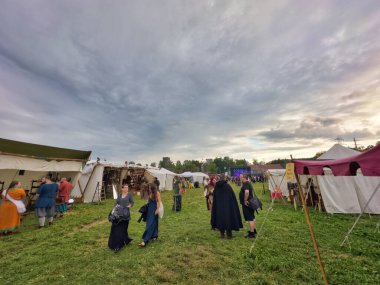 01.06.06.24.Kirchberg.Swizerland. Bir ortaçağ canlandırma etkinliği. Çimenli bir alanda çarpışan zırhlı şövalyeler dramatik bulutlu bir gökyüzü altında izleyicilerle çevrili.