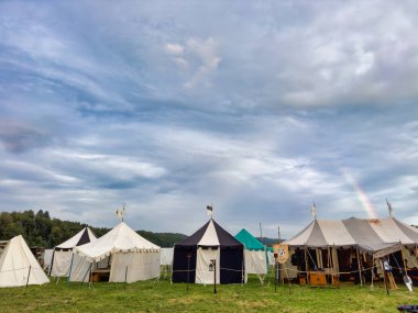 01.06.06.24.Kirchberg.Swizerland. Bir ortaçağ canlandırma etkinliği. Çimenli bir alanda çarpışan zırhlı şövalyeler dramatik bulutlu bir gökyüzü altında izleyicilerle çevrili.
