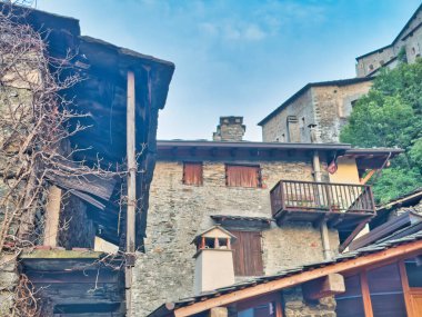 Dağlık bir köyde sakin bir alacakaranlık manzarası. Kırsal evler, parlayan ışıklar ve derin mavi bir gökyüzünün altında yükselen tepeler..