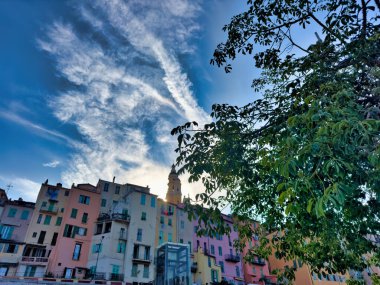 Gün batımında parlayan gökyüzüne karşı kilise kulesi silueti olan renkli Akdeniz binalarının manzarası